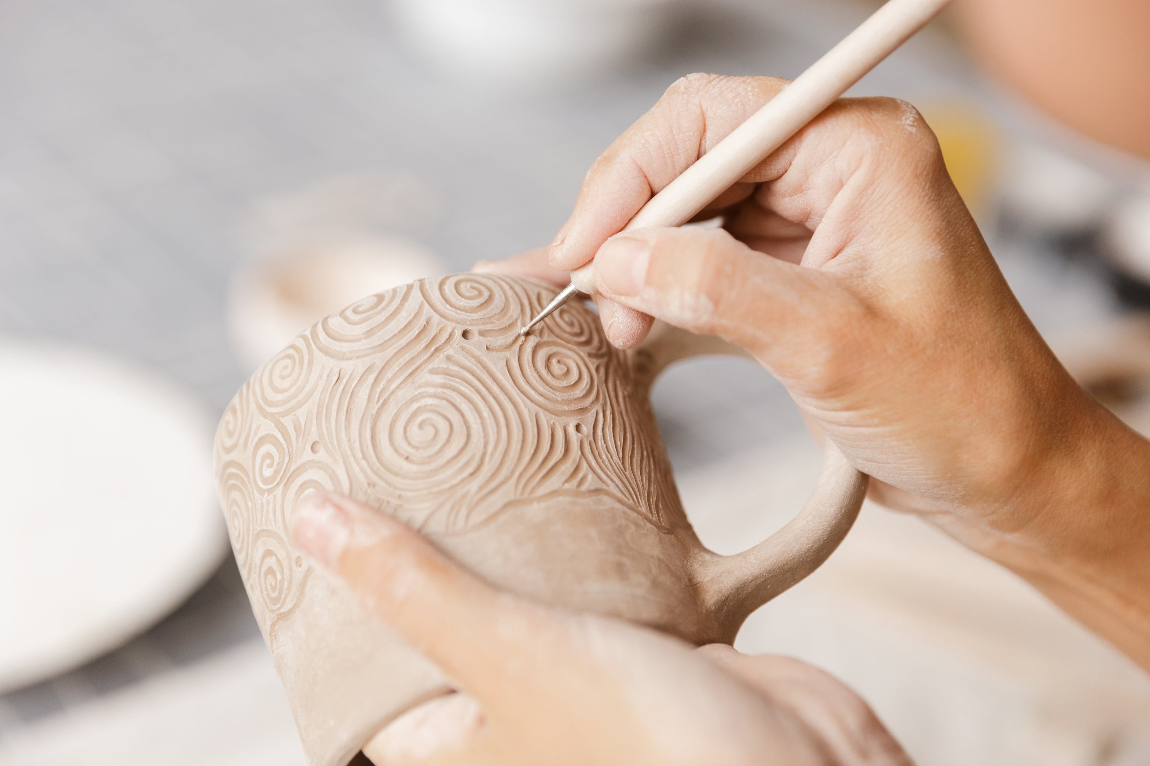 Closeup of artists hand carving a clay mug